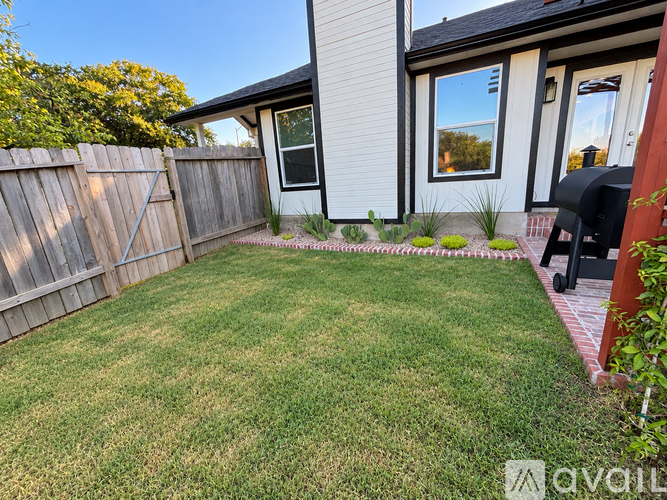 A backyard with a wooden fence and a small lawn.