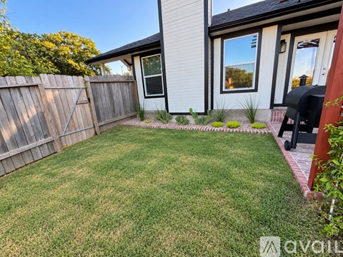 A backyard with a wooden fence and a small lawn.