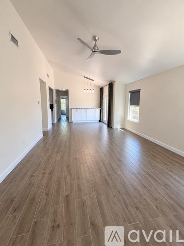 A spacious room with wooden flooring and a ceiling fan.