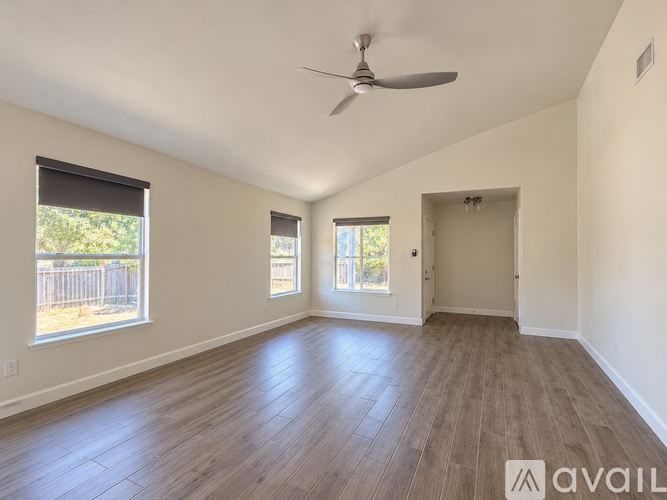 A spacious room with a ceiling fan and wooden flooring.
