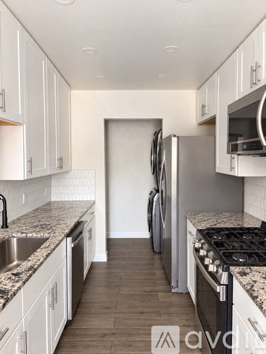 A kitchen with white cabinets and a granite countertop.