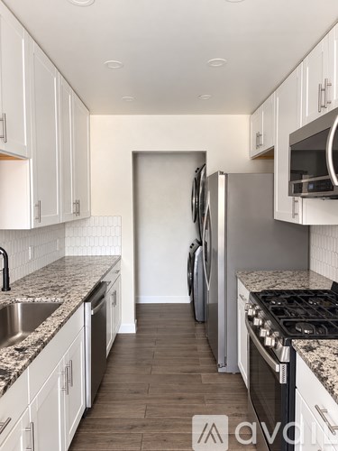 A kitchen with white cabinets and a granite countertop.