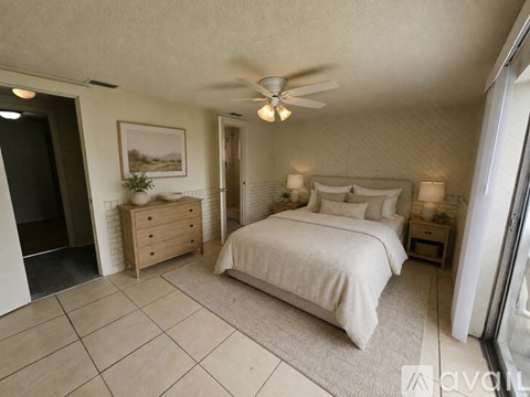 A bedroom with a large bed, a ceiling fan, and a painting on the wall.