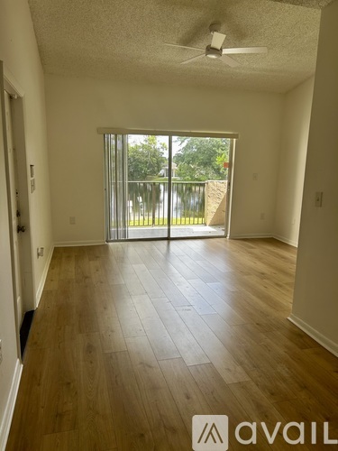 A room with wooden floors and a sliding glass door leading to a backyard.