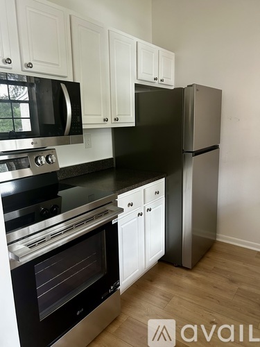 A kitchen with black appliances and white cabinets.