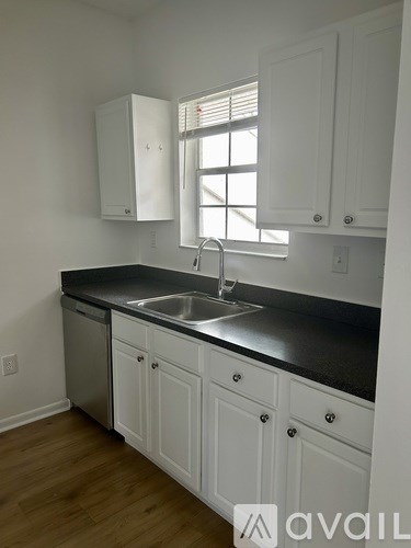 A kitchen with white cabinets and a black countertop.