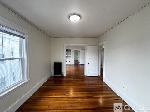 A spacious room with wooden floors and white walls.