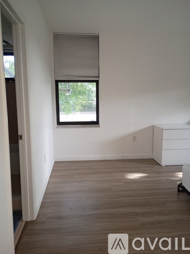 A room with wooden flooring and a window with blinds.