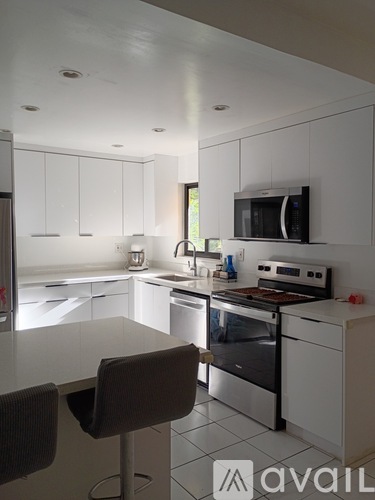 A modern kitchen with white cabinets and appliances.