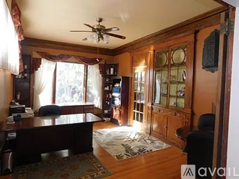A living room with a ceiling fan and a rug on the floor.