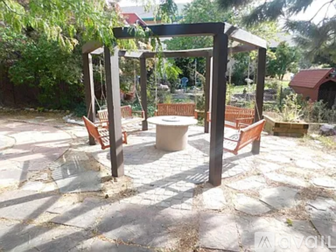 A wooden pergola with a bench and table in a backyard.