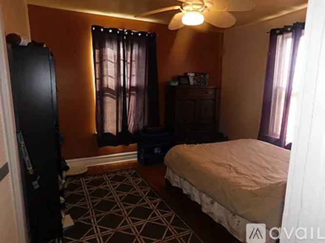 A bedroom with a bed, dresser, and ceiling fan.