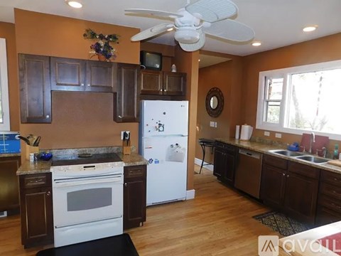 A kitchen with a white refrigerator and a white ceiling fan.