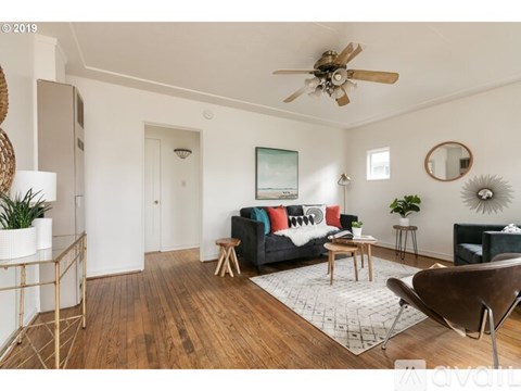 A living room with a black couch and a white rug.