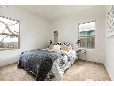 A bedroom with a bed, a small table, and a window.