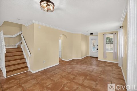 A spacious room with a staircase and a door leading to another room.