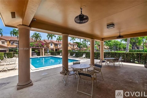 A patio with a table and chairs overlooking a pool.