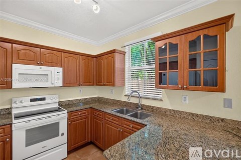 A kitchen with brown cabinets and a granite countertop.
