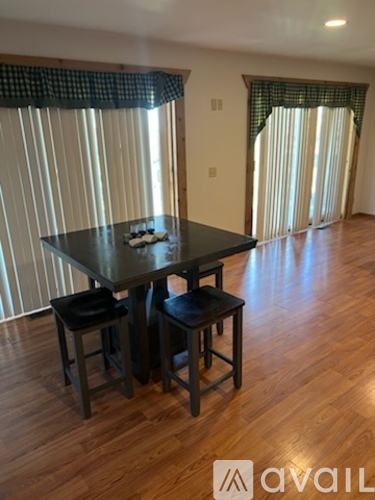 A black dining table with two chairs in a room with wooden flooring.