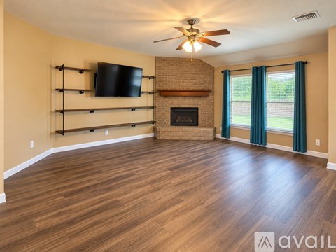 A spacious living room with wood flooring and a brick fireplace.
