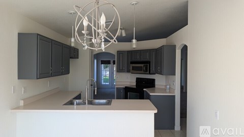 A modern kitchen with a white island and black cabinets.