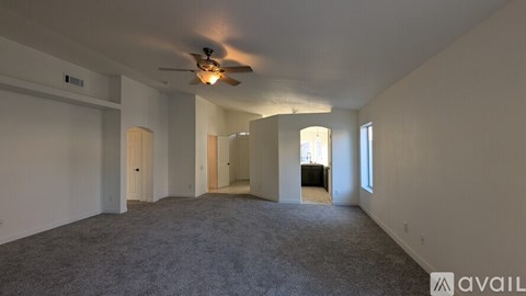 A spacious room with a ceiling fan and carpeted floor.