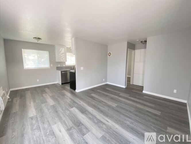 A spacious room with a grey floor and white walls is available for rent.