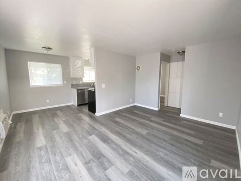 A spacious room with a grey floor and white walls is available for rent.