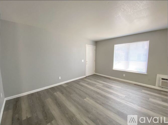 A room with wooden flooring and a window with blinds.