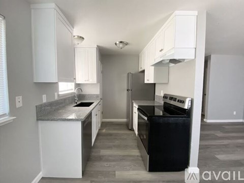 A kitchen with white cabinets and a black fridge.