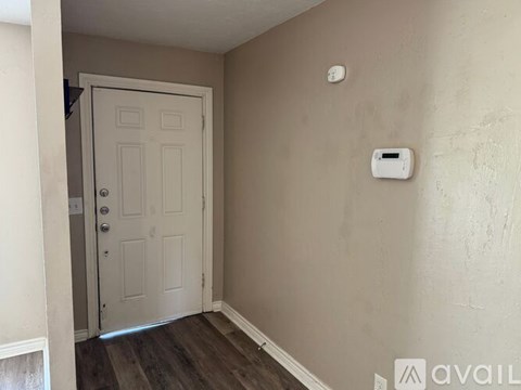 A white door is in a room with a wall-mounted thermostat.