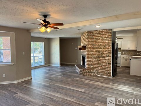 A living room with a brick fireplace and wood flooring.