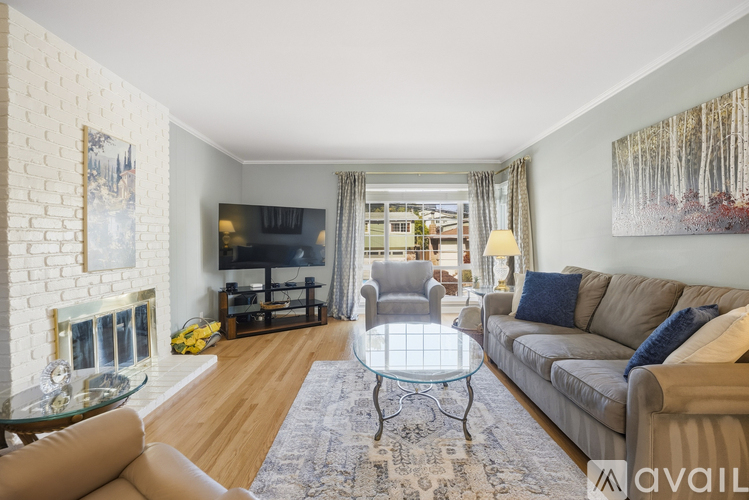 A living room with a glass coffee table and a grey sofa.