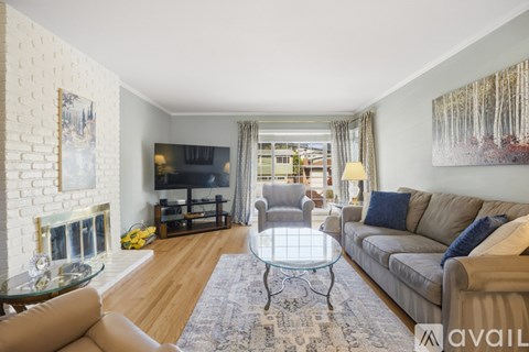 A living room with a glass coffee table and a grey sofa.
