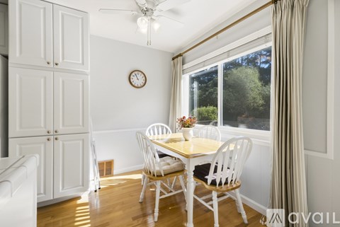 A dining room with a table set for two and a ceiling fan.