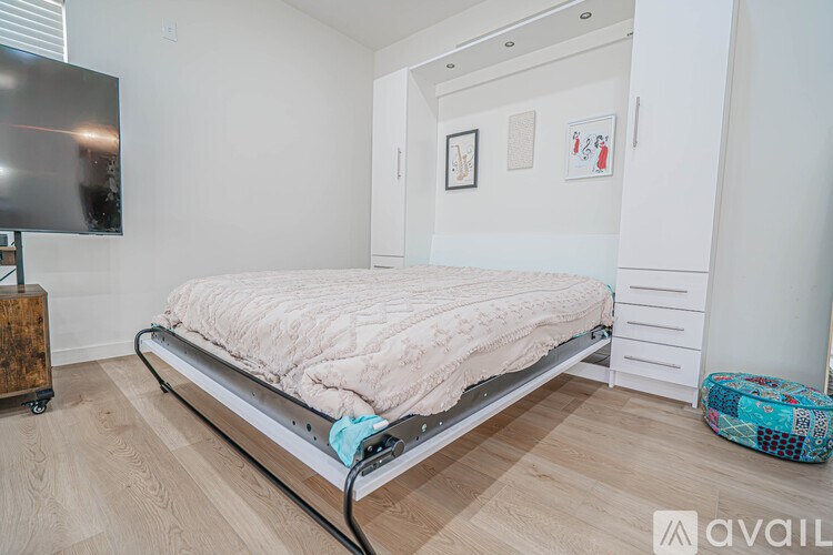 A bed with a white mattress and a white frame is in a room with a wooden floor.