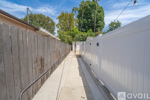 A long white fence runs down the side of a building.