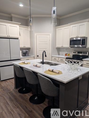 A kitchen with a white countertop and grey chairs.
