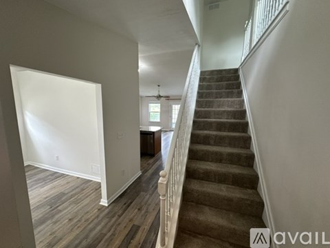 A staircase with a carpeted runner and wooden steps leads up to a landing with a window and a door.