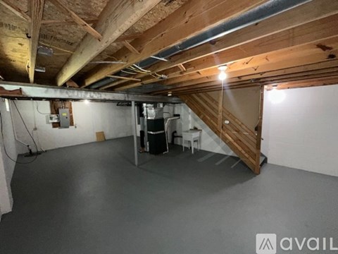 A spacious attic room with a staircase and a workbench.