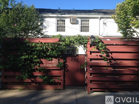 A white house with a red gate and a sign that says "To the" on it.