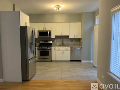 A kitchen with white cabinets and a wooden floor.