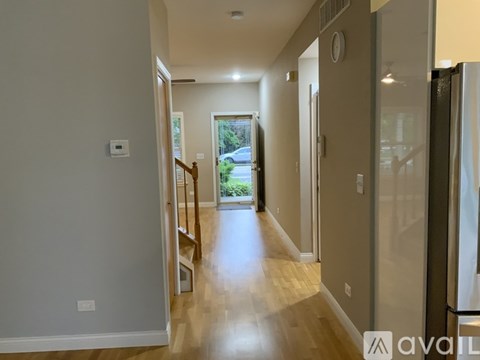 A hallway with a wooden floor and a glass door leading to a balcony.