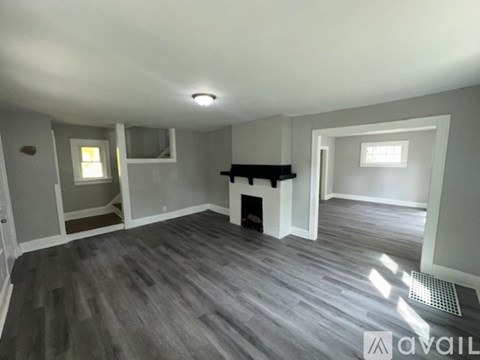 A spacious room with a fireplace and grey flooring.
