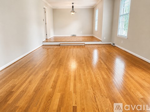A spacious room with wooden flooring and a hanging light fixture.