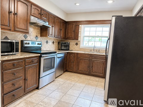 A kitchen with brown cabinets and a black refrigerator.