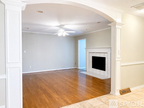 A living room with a fireplace and a ceiling fan.