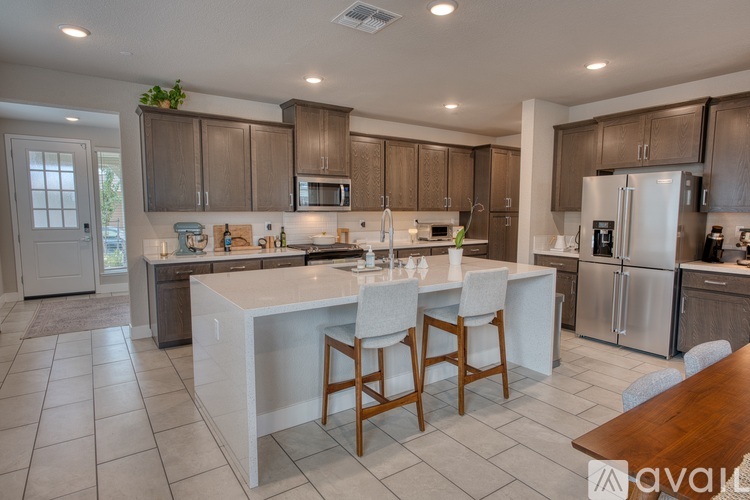 A kitchen with a white island and wooden chairs.