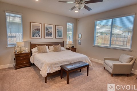 A bedroom with a large bed, a chair, and a ceiling fan.