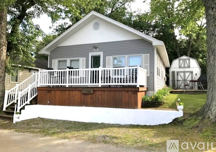 A house with a porch and a tree in front of it.